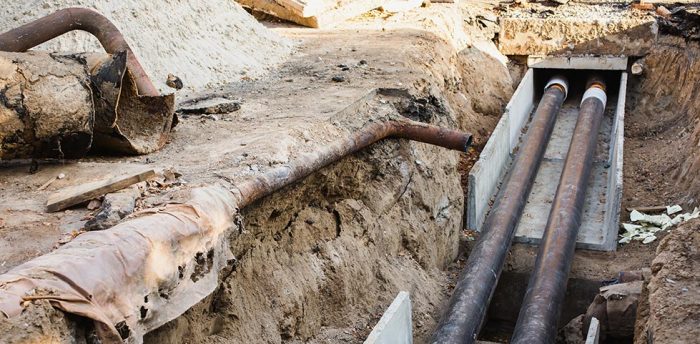 Trench in ground with exposed sewer pipes